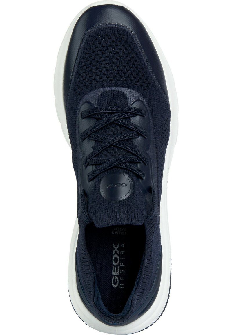 Zapatillas en azul marino con una parte superior de malla, acentos brillantes, cordones redondos, cuello acolchado y una suela de goma blanca con un diseño de textura.