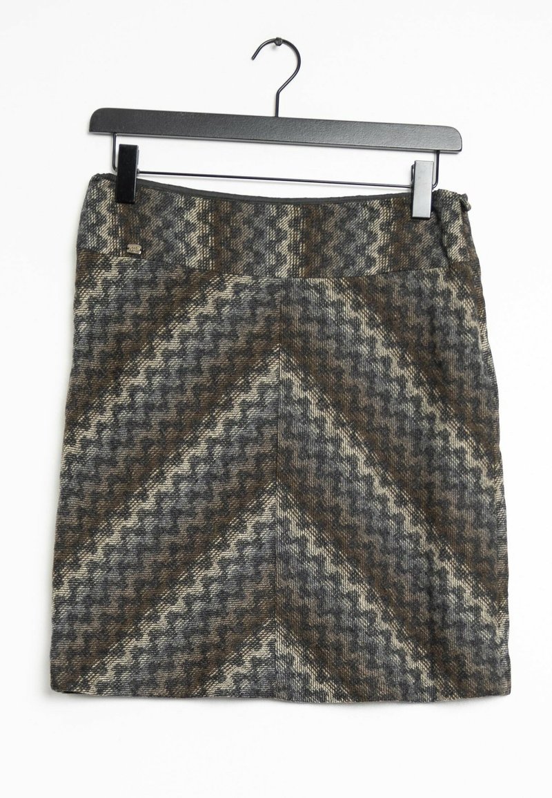 Jupe en laine avec un motif zigzag marron, gris et crème, suspendue sur un cintre noir à pince sur fond blanc.