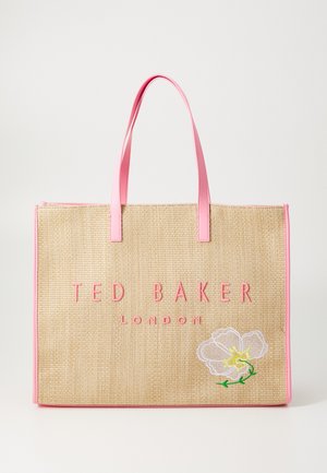 Grote geweven boodschappentas van natuurlijke vezels met roze synthetische handvatten en bies. Bevat een geborduurde witte bloem en merknaam in roze letters.