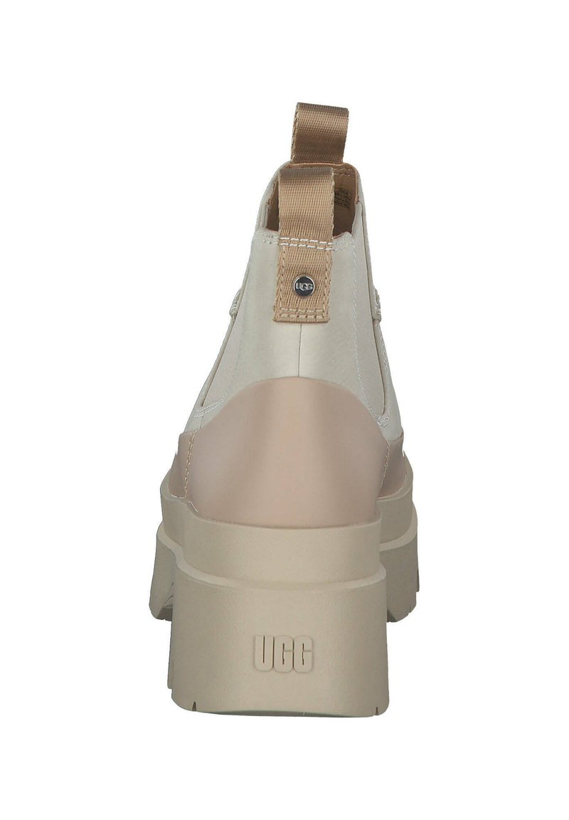 Beige Knöchelschuh mit einem glatten Lederobermaterial, strukturiertem Rückenpanel und minimalistischem Design. Verfügt über eine Schlaufe für einfaches An- und Ausziehen.