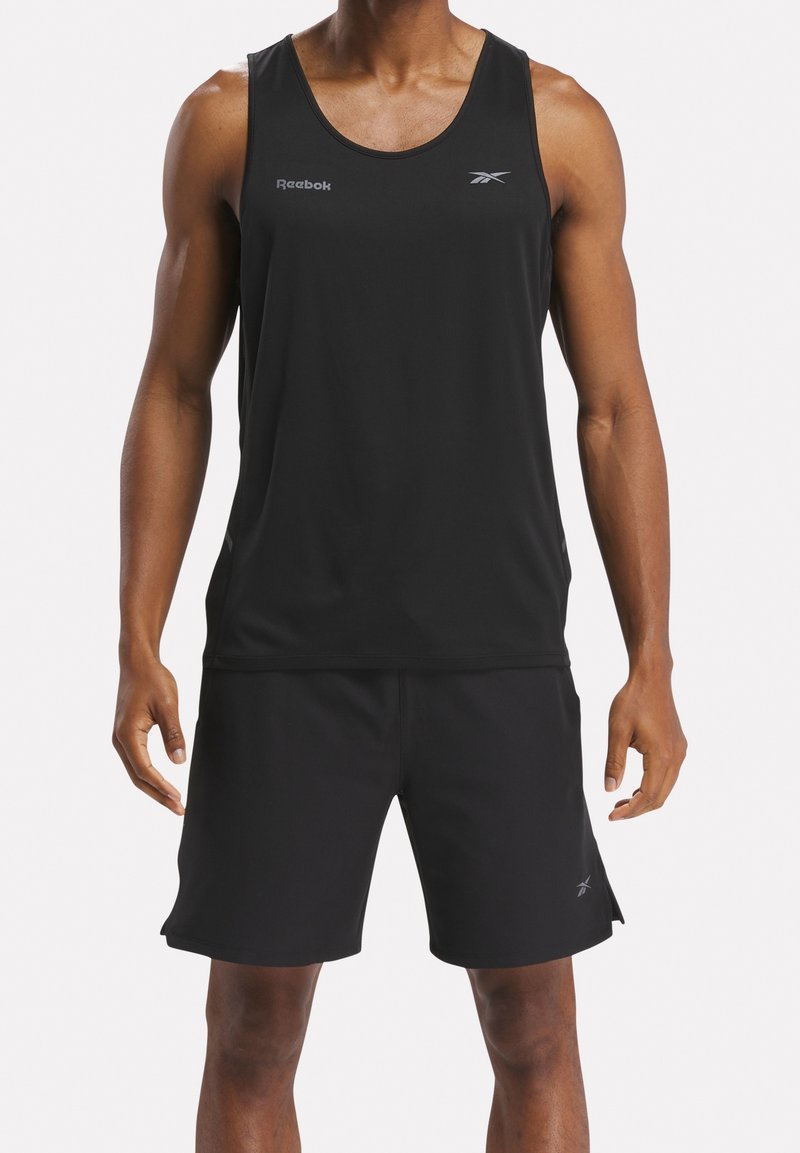 Černý sportovní tílko s kulatým výstřihem a průramky, v kombinaci s černými šortkami. Na obou kouscích se nachází malá značka Reebok.