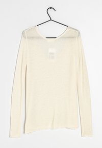 Maglia a maniche lunghe di colore crema, lavorata a maglia, con scollo a barca e orlo grezzo. Tessuto morbido, leggero e leggermente trasparente vicino alle spalle.