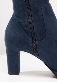 Granatowe zamszowe botki za kostkę z kwadratowym obcasem, bocznym zamkiem, teksturowaną powierzchnią oraz wyprofilowanymi bokami do konturowania stopy.