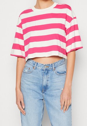 Osoba nosząca krótki różowo-biały pasiasty t-shirt z krótkim rękawem, zestawiony z jasno niebieskimi, wysokim stanem jeansami.