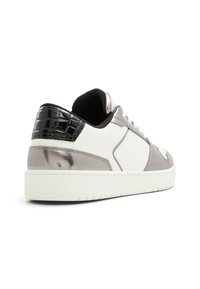 Sneakers con un corpo in morbida pelle bianca testurizzata, dettagli in argento lucido e un tacco in pelle di coccodrillo embossato nero. Suola in gomma e chiusura con lacci.
