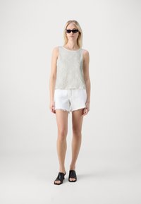 Camiseta sin mangas de textura gris claro, pantalones cortos de mezclilla blanca deshilachada, mocasines negros abiertos por delante y gafas de sol. Diseño simple y minimalista.
