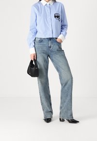 Ljusblå randig skjorta med en svart grafik på bröstet, matchad med blekta blå raka jeans och svarta spetsiga klackar.