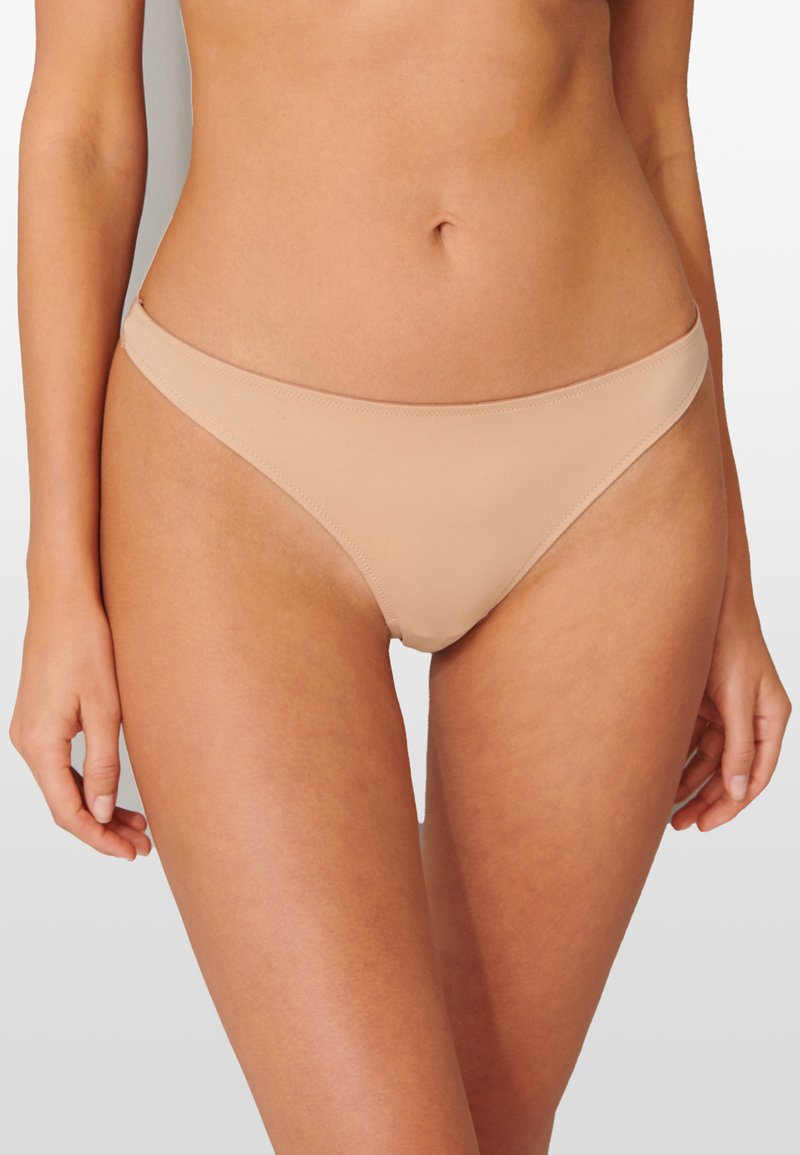 Bas de bikini beige au design minimal, à taille basse et texture lisse. Ne présente aucun motif ni accent matériel.