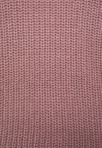 Tessuto lavorato a maglia di un morbido colore rosa con un motivo a coste texturizzato. Il filato appare spesso e uniformemente distribuito, creando un aspetto accogliente.