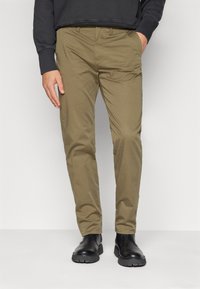 Khaki chinos with a smooth texture, straight leg design, and pockets. Pairing black leather boots features a rubber sole.