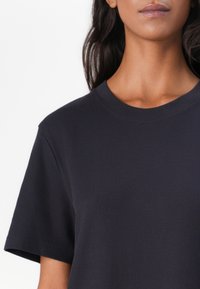 Navyblaue gerippte T-Shirt mit Rundhalsausschnitt und kurzen Ärmeln, aus einem glatten gewebten Stoff gefertigt, mit lockerer Passform.