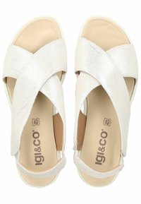 Sandali bianchi con cinturini incrociati, finitura testurizzata e soletta beige liscia. Presentano un design aperto e una suola spessa e bianca.