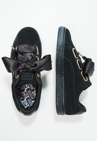 Baskets en daim noir Puma avec larges lacets en ruban de satin et œillets dorés, vues de dessus et de côté sur fond blanc.