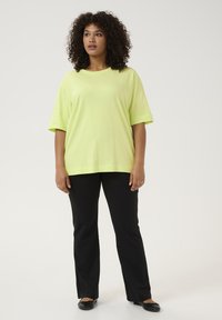 Neónovo žlté oversized tričko z mäkkého materiálu, krátke rukávy, spárované s čiernymi zvonovými nohavicami a čiernymi balerínkami. Jednoduchý a modernos design.