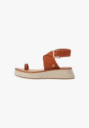 Brown suede sandal with a closed toe, ankle strap, and adjustable buckle. Features a woven jute platform sole and textured detailing.