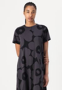 Dark floral dress featuring large, abstract black flowers on a deep charcoal background. Short sleeves and a round neckline. Smooth fabric texture.
