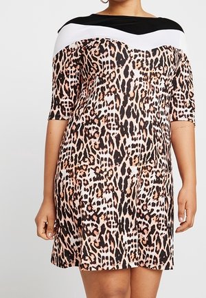 Femme portant une robe courte à manches courtes, longueur genoux, avec un imprimé léopard et un col color block noir et blanc.