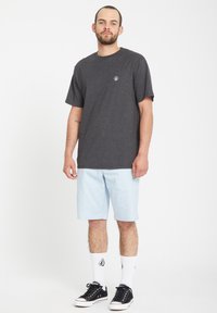 Gray short-sleeve t-shirt with a small logo, light blue shorts, white socks, and black sneakers. Simple, casual outfit.