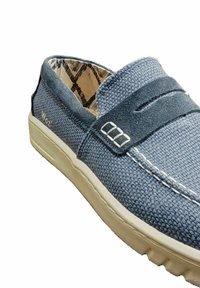 Scarpe slip-on in tela blu con una parte superiore testurizzata, cuciture bianche a contrasto e una fascetta decorativa con dettagli metallici.