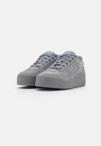 Gray suede sneakers featuring a thick rubber sole, rounded toe, lace-up front, and textured accents on the upper.