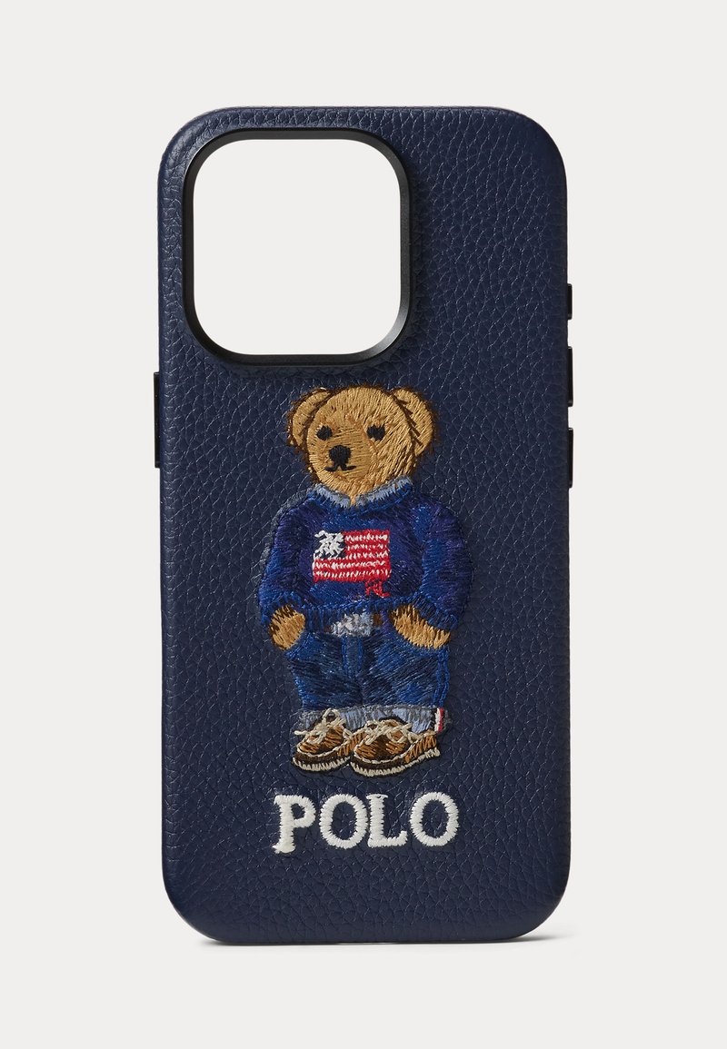 Coque de téléphone texturée bleu marine avec un ours en peluche brodé portant un pull bleu et un jean au-dessus du texte blanc "POLO".