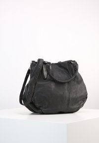 Czarna skórzana torebka na krótkich uchwytach z długim regulowanym paskiem, umieszczona na białym piedestale na tle jednolitego tła.