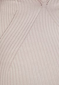 Un tissu côtelé rose clair présente une texture diagonale et des détails perforés. Un tricot lisse et élastique avec un léger brillant, adapté aux vêtements ajustés.