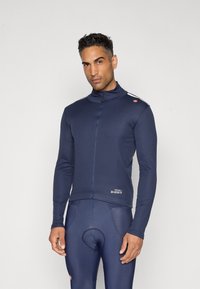 Marineblaue Fahrradjacke mit langen Ärmeln, Reißverschluss und hohem Kragen. Mit einem Logo auf der Schulter und taillierter Passform.