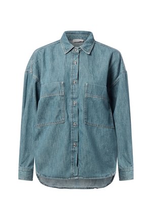 Light blue denim shirt with a button-up front, pointed collar, two chest pockets, and a slightly curved hemline. Soft texture, relaxed fit.