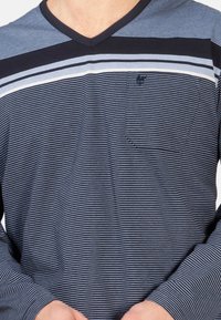 Gestreiftes V-Ausschnitt Langarmshirt in Marineblau und Grau mit einer Tasche auf der linken Brust, das horizontale abwechselnde Streifen und eine weiche Textur aufweist.
