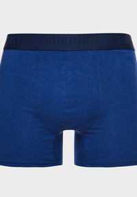 Blauwe katoenen boxershorts met een strak model, voorzien van een marineblauwe elastische tailleband met het merk "SUPERDRY" erin gedrukt. Stijlvolle textuur.