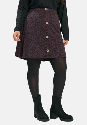 Bordeaux leopard print nederdel med en flared form, prydet med guldknapper fortil. Sammen med sorte strømpebukser og ankel støvler.