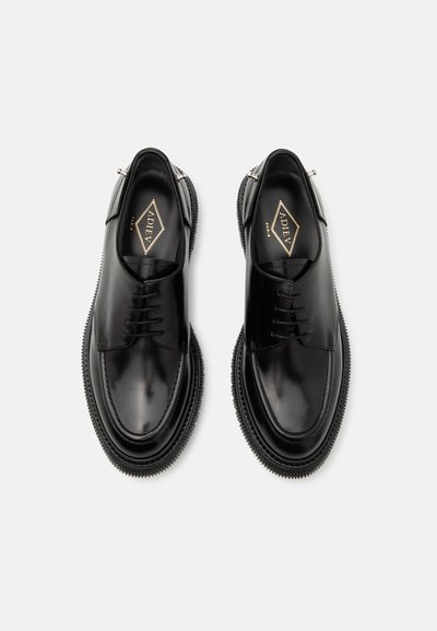 Pantofi negri din piele cu un finisaj neted, vârf rotund, design cu șireturi și talpă texturată în contrast. Branding vizibil în interior.