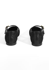 Bottes noires avec un dos en tissu tissé texturé, un devant en cuir lisse, et un petit talon avec une petite boucle dorée sur une sangle de cheville.