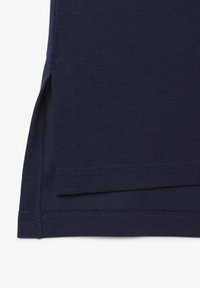 Marinblå pikétröja med texturerad väv, strukturerad design och sidospår vid fållen, samt dubbelstickade sömmar för hållbarhet.