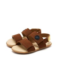 Sandali in suede marrone con due cinturini regolabili in Velcro, una soletta imbottita beige e un accento logo nero sulla fascia anteriore.