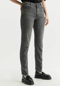 Szare jeansy o wysokim stanie z dopasowaną sylwetką, pi�ęciomaszkowymi kieszeniami, teksturowanym denitem oraz subtelnym, zblakniętym wykończeniem. Połączone z masywnymi, czarnymi loafersami.