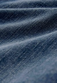 Tela de mezclilla en azul oscuro con una textura suave y un sutil patrón de tejido diagonal, mostrando variaciones naturales en el color.