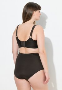 Czarny biustonosz z teksturowanej tkaniny z regulowanymi ramiączkami, w połączeniu z czarnymi majtkami z wysokim stanem, prezentujący gładkie, nieprzezroczyste wykończenie.