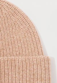 Knit beanie made from soft, light pink yarn with a ribbed texture and folded cuff. Simple design without patterns or accents.
