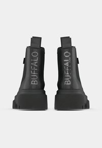 Čierne členkové topánky s robustnou podrážkou, vyrobené z textilu a kože, s embosovaným logom "BUFFALO" na zadnej strane a s ťahacími pútkami.