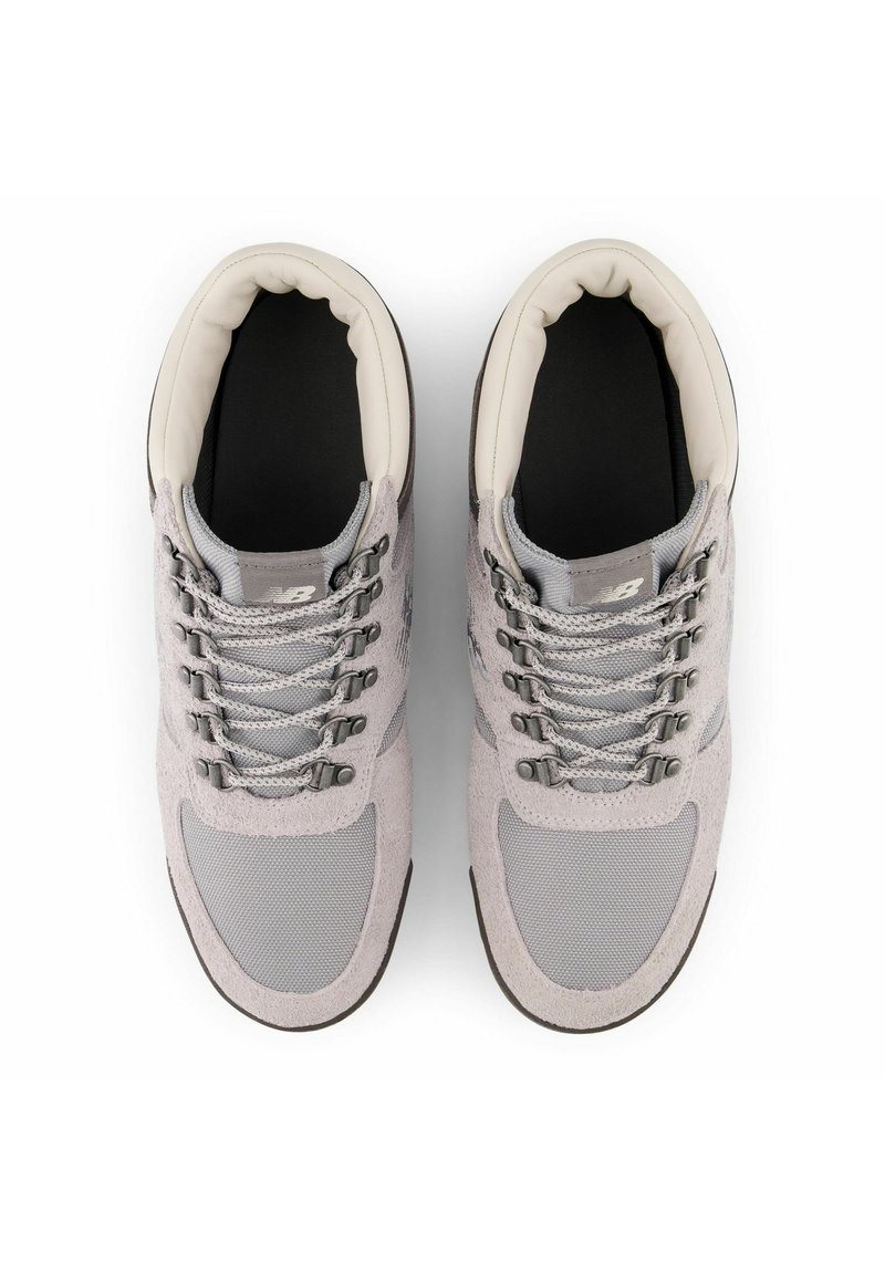 Grijze schoenen met een mix van suede en mesh materiaal, met een gevoerde kraag, grijze veters en een gestructureerde zwarte zool.