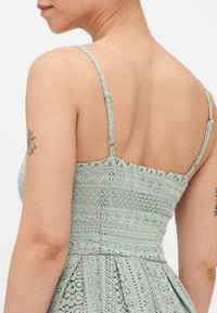 Horgolt ruha világos mentaszínben, állítható pántokkal, texturált mintákkal és egy testhezálló felsőrésszel, ami átmegy egy körszaftos szoknyába.