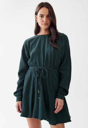 Tume roheline kleit tekstureeritud kangast, millel on lai kaelus, pikad varrukad, stringiga vöökoht ja laiendav seelik.