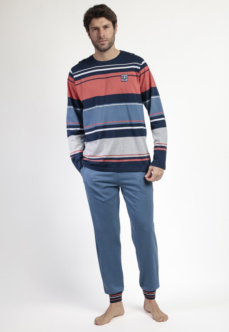 Camisa de manga larga a rayas en rojo, azul marino y gris con cuello redondo; combinada con pantalones de chándal azul con puños acanalados.