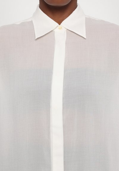 White, lightweight blouse with a classic collar and button front. The fabric appears sheer with a smooth texture and subtle sheen.