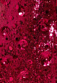 Tissu à sequins rose vif avec des sequins de forme circulaire et en fleur, créant une surface texturée et scintillante.