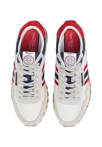 Bijele platnene tenisice s mornarsko plavim i crvenim detaljima, s vezanjem, teksturiranim materijalima i gumiranim potplatom. Logotip na jeziku.