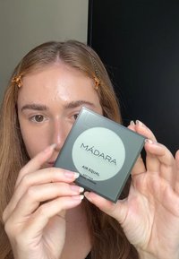 Polvo mineral de seda suave MÁDARA en un estuche cuadrado negro con una etiqueta verde que presenta un gran círculo blanco. El texto incluye "AIR EQUAL" y detalles del producto.