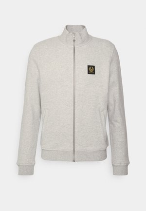Lys grå zip-up sweatshirt med høj krave, ribbede manchetter og en frontlomme. Har et sort logo-patch på brystet.